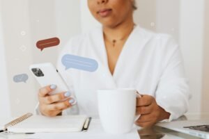 Close-up of a person using a smartphone while holding a coffee cup, showcasing digital communication.