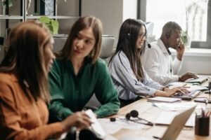 A diverse group of call center employees collaborating with headsets and computers.