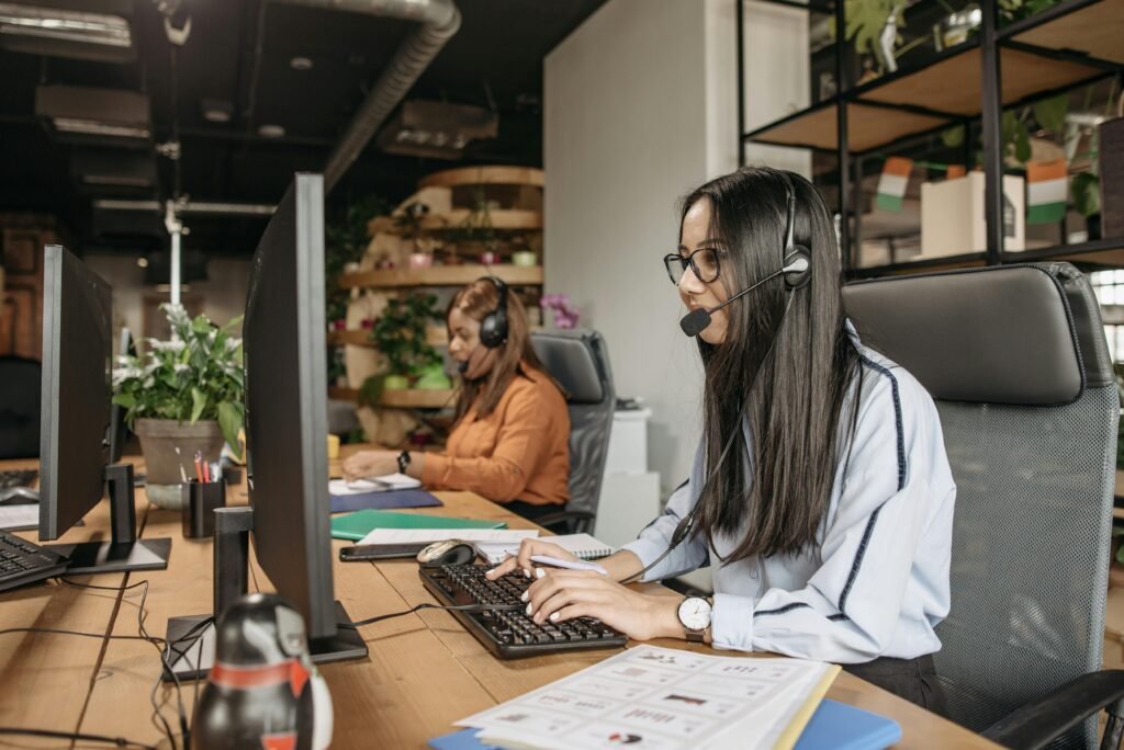 Two women in a modern call center working on computers, providing customer service.