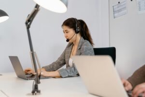 Focused woman at a desk with a headset, providing customer support in an office setting.