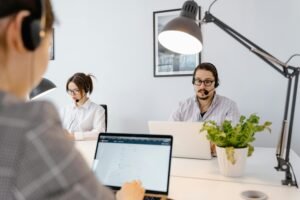 Professional call center agents working on laptops in a bright modern office.